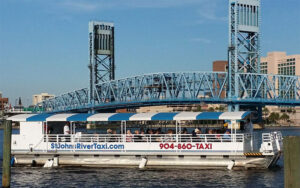 river boat on water with bridge and buildings behind at st johns river taxi jacksonville