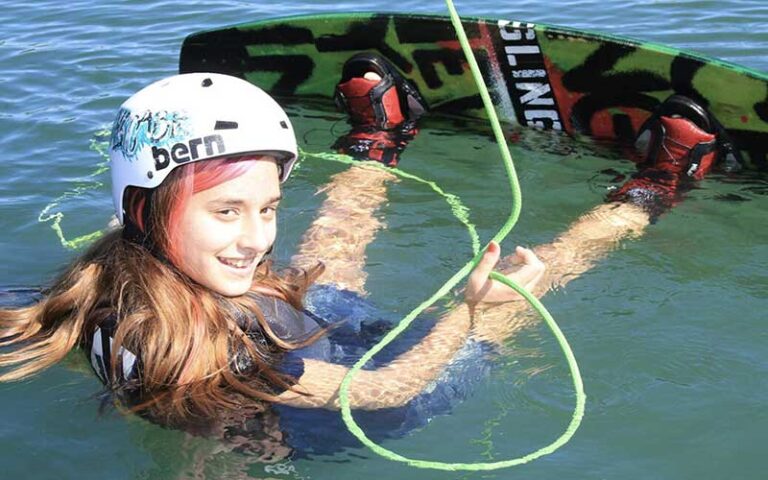 smiling girl in water strapped to wakeboard at keys cable park marathon
