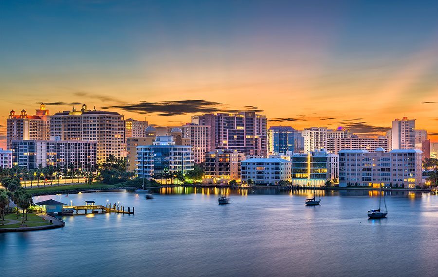 sunrise with orange sky through downtown sarasota skyline over bay