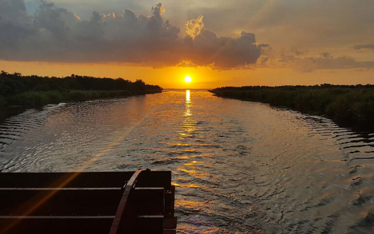 sunset over water with dark tree line on sides at st johns rivership co sanford