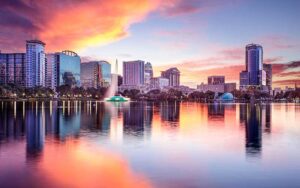 sunset with colorful sky and lake with fountain and skyline at lake eola park orlando