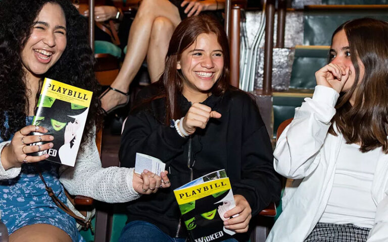 teenage girls laughing at performance with playbills for wicked at adrienne arsht center for the performing arts miami