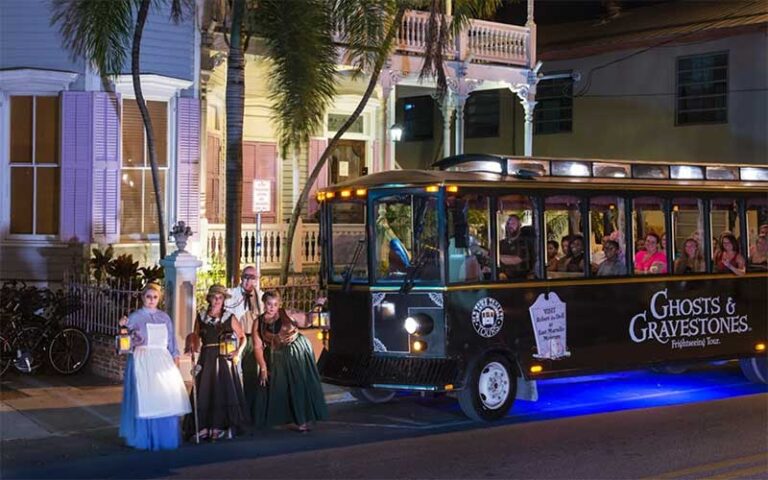 trolley with ghosts on street with houses at ghosts and gravestones tour key west