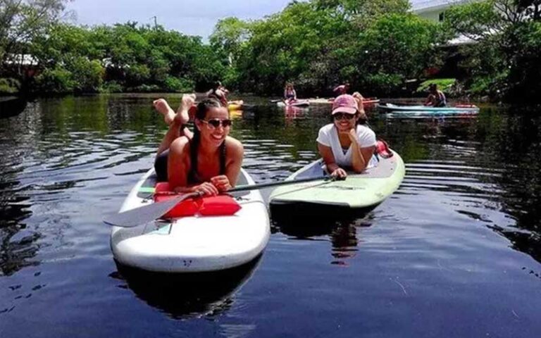 two women laughing and lying on paddle boards at sunrise paddleboards fort lauderdale