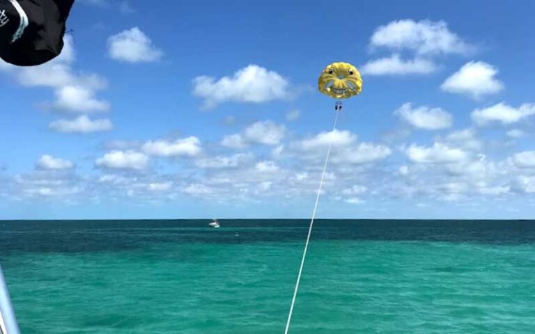 view from boat of parasailors with yellow face chute over ocean at z flight parasail watersports marathon fl keys