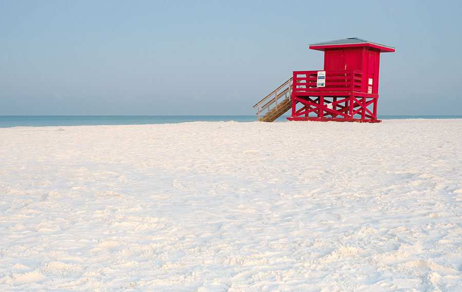 white sand beach with blue water and red lifeguard tower siesta key beach sarasota