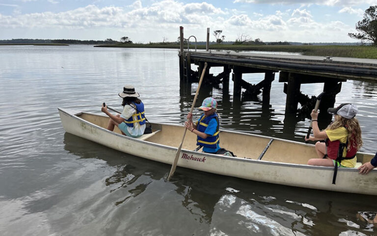 young canoers launching on water beside dock at betz tiger point preserve jacksonvile