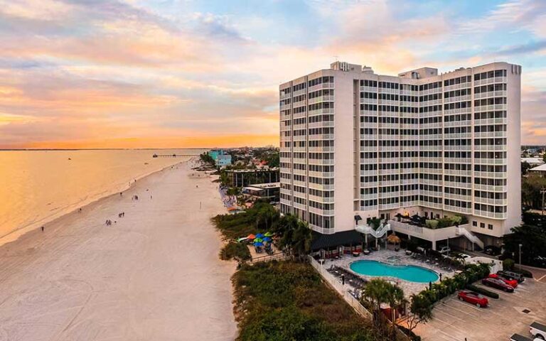 aerial exterior of hotel with pool along beach with sunset sky at diamondhead beach resort fort myers