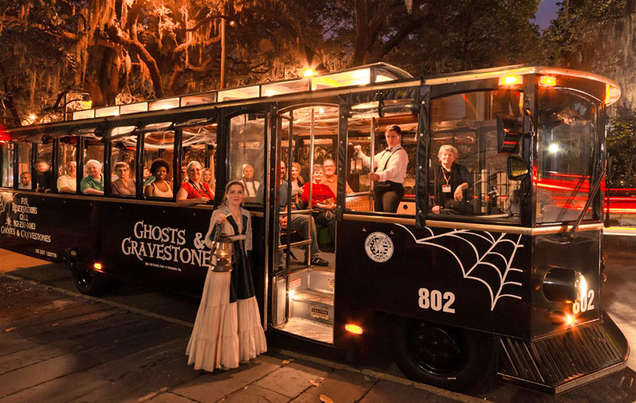 black trolley bus at night with low lighting and ghost character with lantern at door ghosts and gravestones tour key west