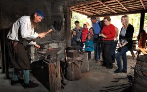 blacksmith in period dress hammering with onlookers at colonial quarter st augustine