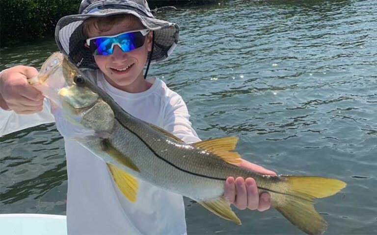 boy holding caught bass on boat at salty native charters fort myers