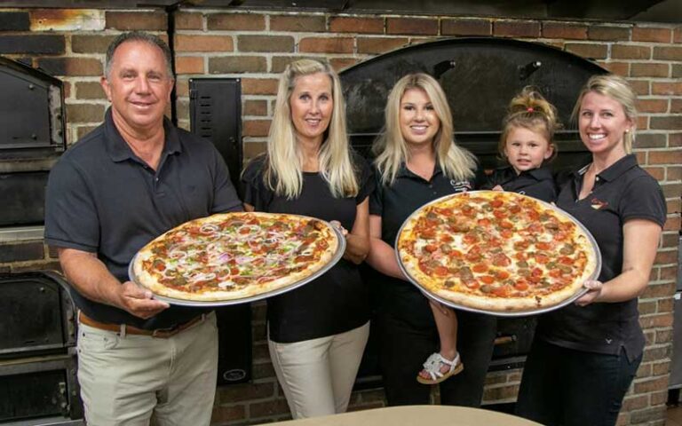 carmelo family holding huge pizza at carmelos pizzeria st augustine