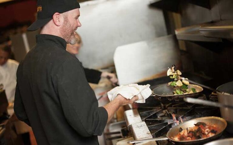 chef in kitchen tossing ingredients in saucepan at pizzalleys chianti room st augustine