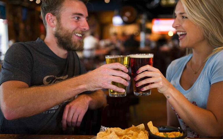 couple toasting draft beers with nachos at fords garage fort myers
