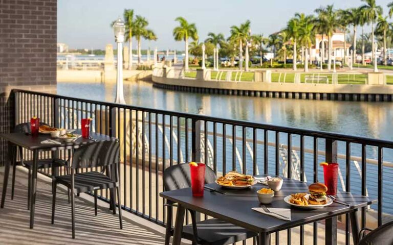 dining tables outdoor patio along fence with river view at luminary hotel and co fort myers