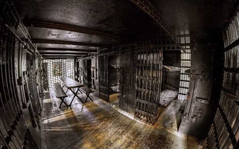 empty jail cell with black bars and metal table at old jail museum st augustine