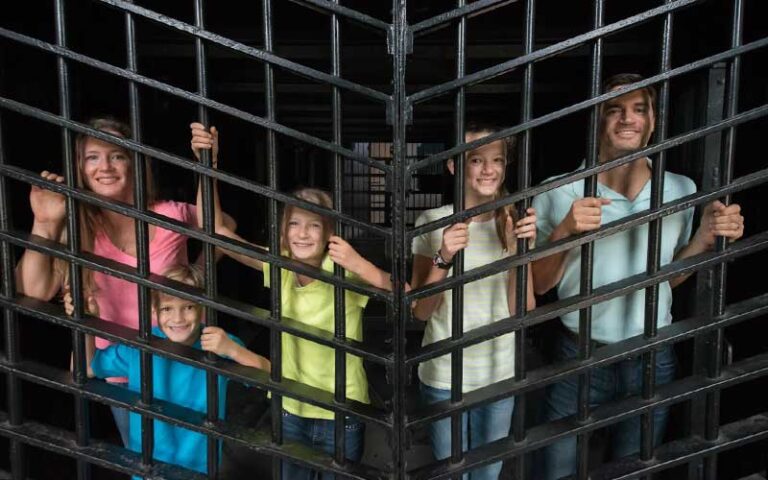 family of four looking through bars of iron gate at old jail museum st augustine