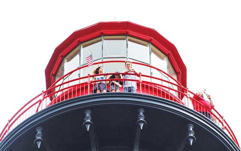 family of three looking out from railing ground view at st augustine lighthouse maritime museum