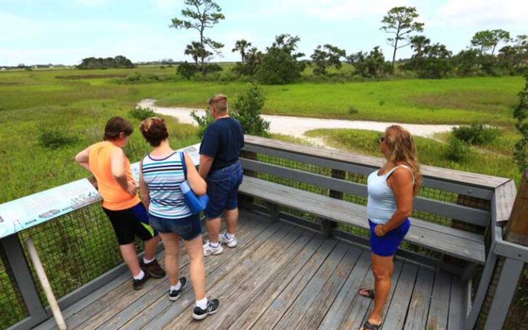 family on boardwalk looking out across wetlands area at fort mose state park st augustine