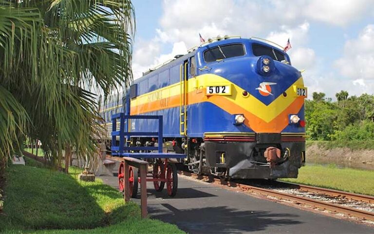 front of blue and yellow train on tracks ready to board at murder mystery dinner train fort myers