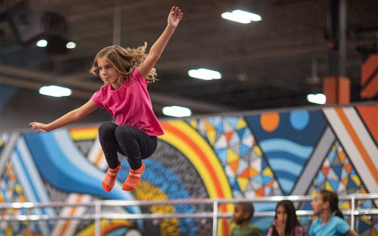 girl with hangtime over trampoline with friends seated behind at sky zone trampoline park fort myers