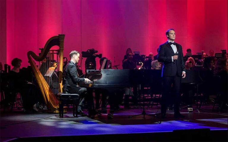 grand piano with orchestra behind on stage and male singer at gulf coast symphony fort myers