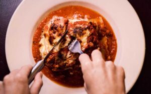 hands cutting parmigiana at pizzalleys chianti room st augustine