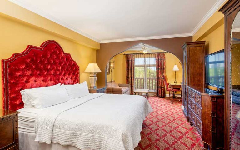 king bed suite with red and gold accents at casa monica resort spa st augustine