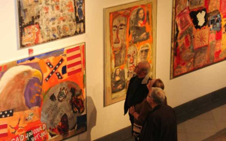 men viewing several art pieces on wall of exhibit at sidney and berne davis art center fort myers
