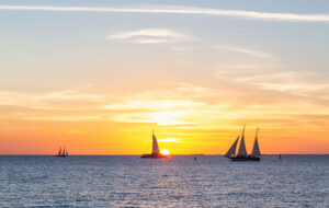 orange and yellow sunset over water with catamarans and sailboats mallory square key west