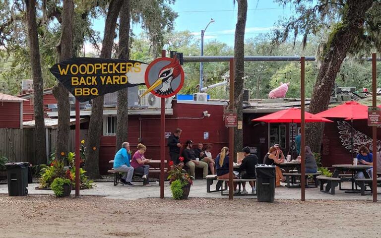 outdoor patio seating with diners and sign at woodpeckers backyard bbq st augustine
