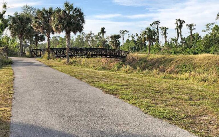 paved path with metal bridge spanning canal at john yarbrough linear park fort myers