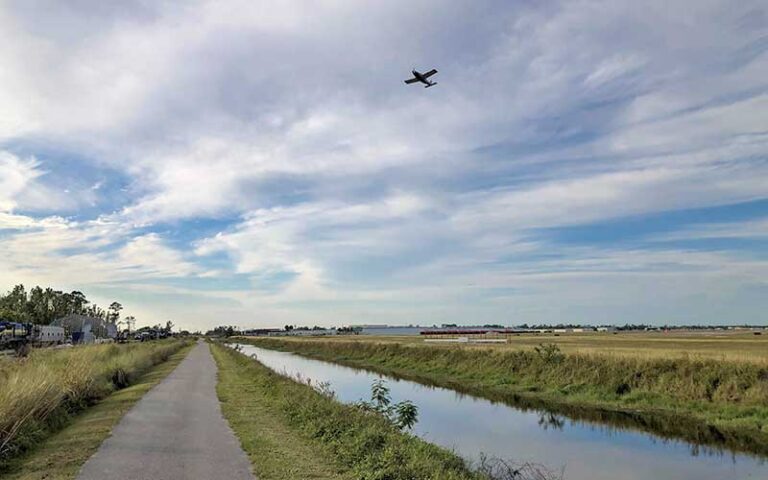 plane taking off from neighboring airport above paved trail and waterway at john yarbrough linear park fort myers