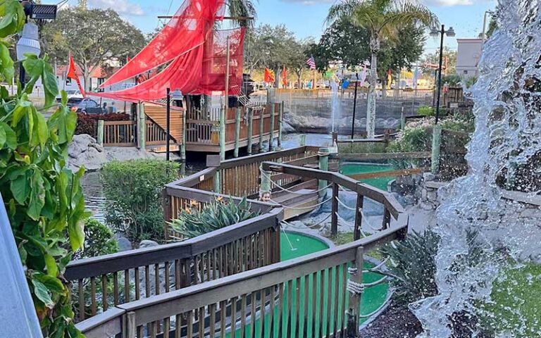 putting green leading down boardwalk near waterfall at smugglers cove adventure golf fort myers beach