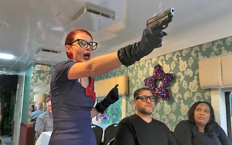 redheaded woman pointing gun in dining car of train at murder mystery dinner train fort myers