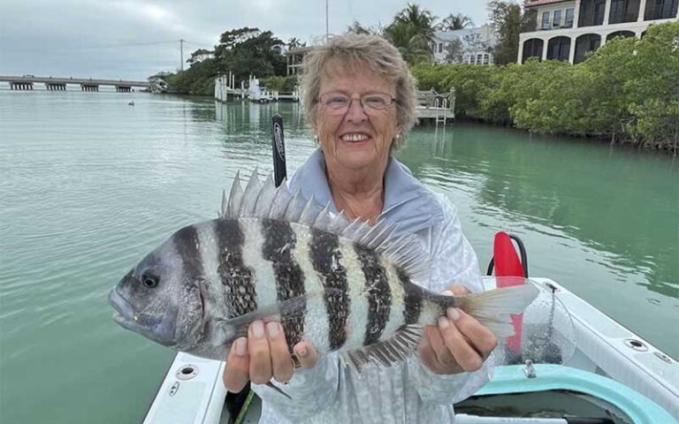 senior lady on boat holding zebra striped fish at salty native charters fort myers