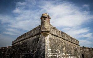 stone wall of fort with turret centered against cloudy sky at castillo de san marcos st augustine