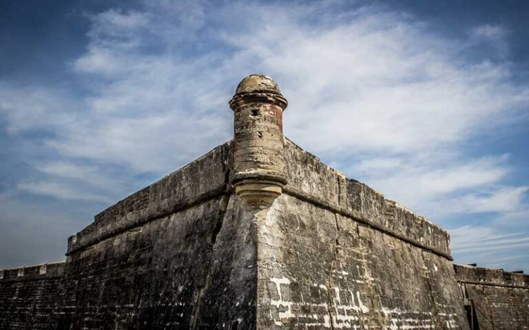 stone wall of fort with turret centered against cloudy sky at castillo de san marcos st augustine