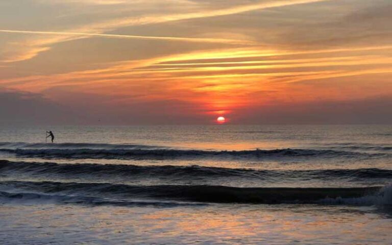 sunrise over ocean with paddle boarder silhouette at anastasia state park st augustine