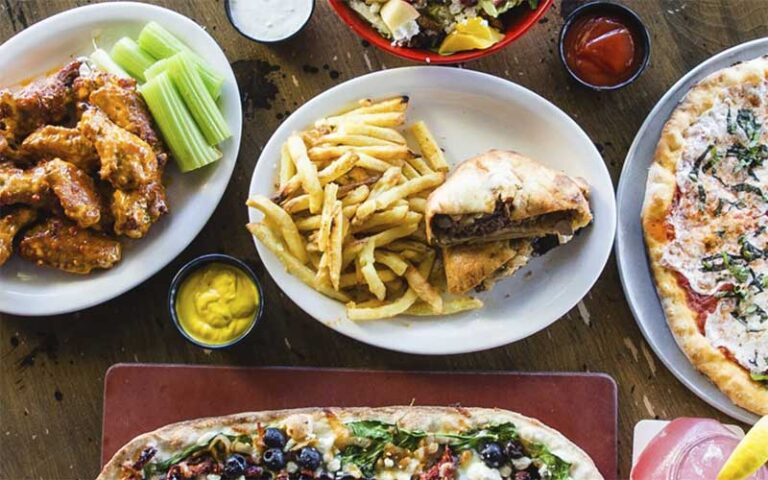 table with multiple entrees of flatbread wings pizza and sandwiches at miromar outlets fort myers