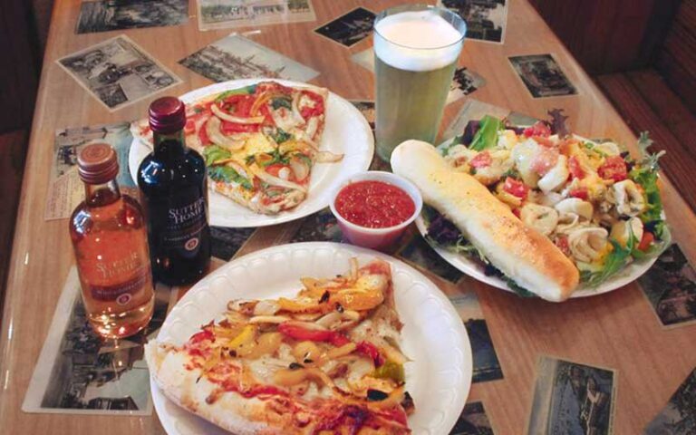 three loaded slices on table with beer and wine at pizzalleys chianti room st augustine
