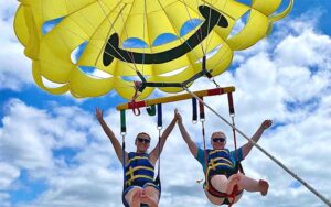 two riders with arms up smiling at paradise parasail fort myers beach