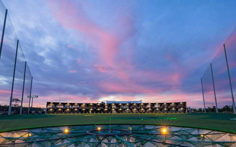 two stories of driving bays with sunset sky at topgolf fort myers