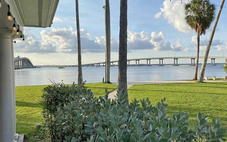 view across landscaped lawn with bench and trees and inlet with bridges at burroughs home and gardens fort myers