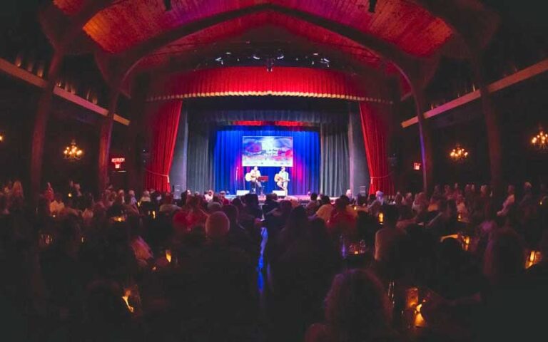 view from back of dark venue with two seated guitarists on stage at key west theater