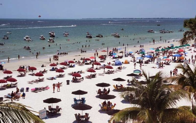 view from hotel beach with rows of umbrellas and boats in water at lana kai island resort fort myers beach