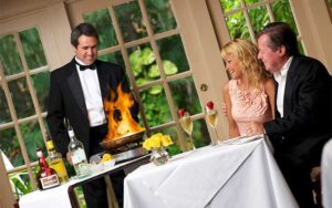 waiter in formalwear prepping flambe at cart with dining couple looking on at the veranda fort myers