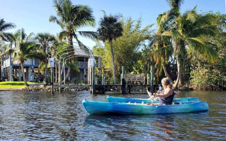 women paddling kayaks with dock and house on bank at manatee park fort myers