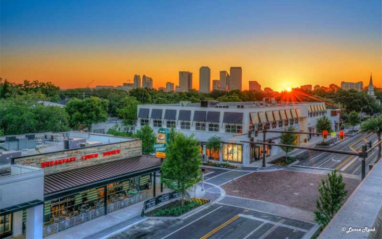 aerial view of open air shopping district with city skyline in distance and sunrise sky at hyde park village tampa