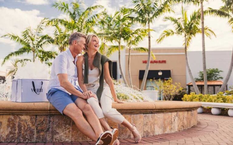 couple laughing sitting on fountain in outdoor shopping area at shops at pembroke gardens ft lauderdale